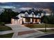 Beautiful two-story home with a three-car garage, manicured lawn, and appealing curb appeal at dusk at 320 Dodd Ln, Alpharetta, GA 30005