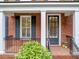 Close up of charming front porch featuring brick, white columns, and black railings and shutters at 5000 Davenport Pl, Roswell, GA 30075