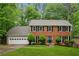 Charming two-story brick home featuring a well-manicured lawn, mature trees, and a two-car garage at 745 Greenvine Pl, Roswell, GA 30076