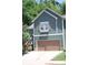 Charming home featuring green siding, a brown garage door, and a window box filled with flowers at 313 India Ln, Canton, GA 30114
