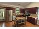 Well-lit kitchen boasts stainless steel appliances, granite countertops, a kitchen island and burgundy cabinets at 313 India Ln, Canton, GA 30114
