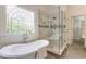 Luxurious bathroom featuring a soaking tub, glass-enclosed shower, and decorative window, offering a spa-like experience at 4561 Jenkins Way, Douglasville, GA 30135