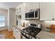 Well-lit kitchen showcasing stainless steel gas range, microwave, herringbone backsplash, and white cabinetry at 4561 Jenkins Way, Douglasville, GA 30135