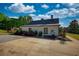 Side view of modern farmhouse with a black roof and gravel driveway at 540 Benton Rd, Covington, GA 30014