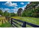 Expansive land with lush greenery and a charming black fence under a bright, cloudy sky at 540 Benton Rd, Covington, GA 30014