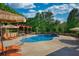 Backyard pool with lounge chairs, wooded surroundings, pergola with bar, and a sunny sky at 540 Benton Rd, Covington, GA 30014
