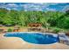 Backyard pool with lounge chairs, wooded surroundings, pergola with bar, and a sunny sky at 540 Benton Rd, Covington, GA 30014