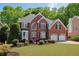 Stately brick home shows off a lush lawn, mature trees, and a practical two-car garage at 1105 Anemone Nw Way, Acworth, GA 30102