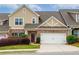 Charming townhome featuring a two-car garage, brick accents, manicured landscaping, and inviting curb appeal at 2141 Slick Stone Dr, Snellville, GA 30078