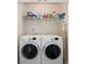 Modern laundry room with front-load washer and dryer and overhead shelving for storage at 2141 Slick Stone Dr, Snellville, GA 30078