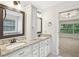 Bathroom featuring double vanity with granite counters, framed mirrors, and an open view to the main bedroom at 3463 Dunbar Ln, Suwanee, GA 30024