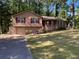 Split level home with brown siding, red shutters, and an attached garage on a wooded lot at 4865 Surrey Dr, Roswell, GA 30075