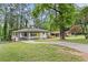 A cozy ranch-style home with a long driveway, carport, and beautiful yard surrounded by trees at 2148 Meador Se Ave, Atlanta, GA 30315
