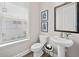 Well-lit powder room with a pedestal sink and a decorative mirror at 964 Catamaran Ct, Alpharetta, GA 30005