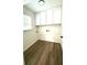 Bright laundry room with wood-look floors, white cabinets, and a window bringing in natural light at 313 Summit Ridge Dr, Lawrenceville, GA 30046