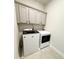 Well-organized laundry room with overhead cabinets and modern, matching washer and dryer at 4736 Landing Water Path, Buford, GA 30519