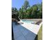 View of the pool and patio area with several lounge chairs, set against a backdrop of lush greenery at 4736 Landing Water Path, Buford, GA 30519