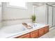Soaking tub with tile surround and wood cabinets in light-filled bathroom at 55 Little Barley Nw Ln, Grayson, GA 30017