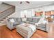 An inviting living room with hardwood floors, a comfortable gray sectional sofa, and a view into the open-concept kitchen at 55 Little Barley Nw Ln, Grayson, GA 30017