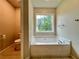Bright bathroom featuring soaking tub under window, nearby toilet, and tile flooring at 655 Wellingborough Ct, Alpharetta, GA 30005