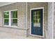 Close-up of the front door with glass paneling, complemented by the surrounding gray brick facade and trim at 3970 Brushy St, Powder Springs, GA 30127
