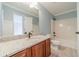 Well-lit bathroom featuring granite counters, wood cabinets, and a shower-tub combo at 1349 Mckinsey Rdg, Loganville, GA 30052
