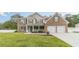 Inviting two-story brick home with a manicured lawn, covered front porch, and a two-car garage at 1349 Mckinsey Rdg, Loganville, GA 30052