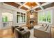 A cozy living room with hardwood flooring, stone fireplace, coffered ceilings, and large windows at 939 Middle Fork Trl, Suwanee, GA 30024