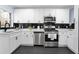 Updated kitchen with white cabinets, black subway tile backsplash, stainless steel appliances, and black hardware at 1931 Selwyn Dr, Decatur, GA 30035