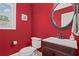 Stylish half bathroom with red walls, a decorative mirror, and modern fixtures at 7493 Elderberry Dr, Douglasville, GA 30135