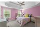 Cozy bedroom with pink walls, carpet, ceiling fan, and natural light streaming through the windows at 7493 Elderberry Dr, Douglasville, GA 30135