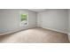 Bright bedroom featuring neutral carpet, pale grey walls, window with green tree view and a white door at 2828 Cloverhurst Dr, Atlanta, GA 30344