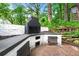 An outdoor kitchen with a large brick fireplace and cooking area surrounded by lush greenery at 2828 Cloverhurst Dr, Atlanta, GA 30344