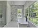 Elegant bathroom with marble accent wall, soaking tub, glass shower, and bright natural light at 3599 Centerville Rosebud Rd, Snellville, GA 30039