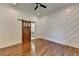 Bedroom with sliding barn door, detailed wall, hardwood flooring, and ceiling fan at 3599 Centerville Rosebud Rd, Snellville, GA 30039