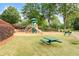 Community playground featuring a slide, climbing structure, and swing set surrounded by lush green trees and landscaping at 3640 Ridgeway Ter, Suwanee, GA 30024