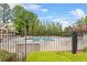 Community pool area enclosed by a black iron fence, surrounded by mature trees and ample seating at 3640 Ridgeway Ter, Suwanee, GA 30024