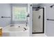 A sleek bathroom featuring a soaking tub with black fixtures, and a walk-in shower with glass door at 3798 Kirkwood Nw Run, Kennesaw, GA 30144