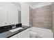 Neat bathroom featuring a tub, a shower with gray tile, black countertops, and a white vanity at 4206 Townsend Ln, Atlanta, GA 30346