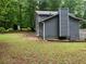 Back exterior of the home featuring neutral siding, white trim, a brick chimney, and a wooded backdrop at 486 Victoria Rd, Woodstock, GA 30189