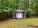 A cozy outbuilding with a small porch sits peacefully in the wooded backyard at 486 Victoria Rd, Woodstock, GA 30189