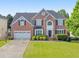 Traditional two-story brick home featuring a well-maintained lawn, two-car garage, and beautiful landscaping at 1730 Millhouse Run, Marietta, GA 30066