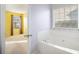 Bright bathroom with a soaking tub under a window with blinds and a view to the bedroom at 7492 Ferrara Dr, Lithonia, GA 30058