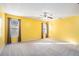 Large bedroom with bright yellow walls, neutral carpet, ceiling fan, and two large windows at 7492 Ferrara Dr, Lithonia, GA 30058