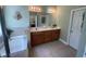 Bright bathroom featuring dual sinks, soaking tub, decorative accents, and tile flooring at 140 Puckett Creek Dr, Canton, GA 30114