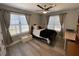 Comfortable bedroom featuring a ceiling fan, two windows with curtains, and hardwood floors at 140 Puckett Creek Dr, Canton, GA 30114