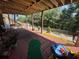 View of the covered patio featuring red tile, wooden supports, and multiple plants at 140 Puckett Creek Dr, Canton, GA 30114
