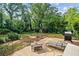 Lush backyard featuring a patio area with a grill, lounge chair, and fire pit, all surrounded by mature trees at 1759 Kimberly Sw Dr, Marietta, GA 30008