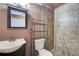 Traditional bathroom featuring tile shower, toilet with shelving unit, and dark framed mirror over sink at 7933 Heathmore Dr, Fairburn, GA 30213