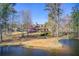 Beautifully landscaped home overlooking a serene lake with mature trees and green lawn at 7933 Heathmore Dr, Fairburn, GA 30213